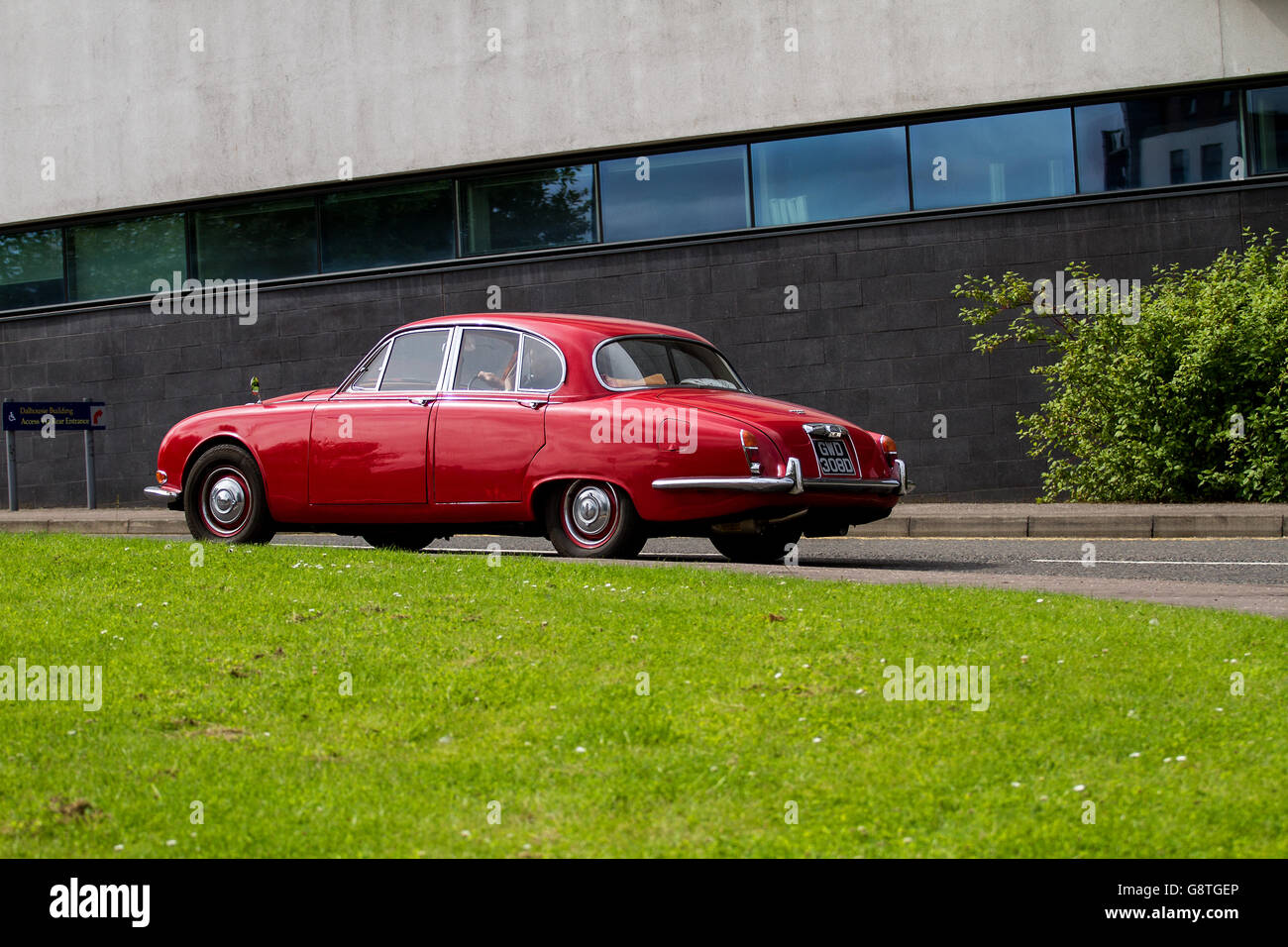 A red 1960`s vintage Jaguar 420 saloon car traveling past the Abertay